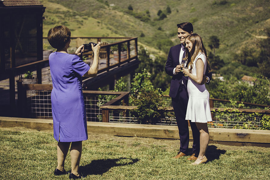 Una signora che fotografa una coppia in giardino